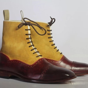Può includere: Stivaletti in pelle bicolore, giallo senape e bordeaux. La parte superiore è in pelle scamosciata giallo senape, mentre la parte inferiore e la punta sono bordeaux. Lacci marroni e motivo cucito decorativo sulla sezione bordeaux.