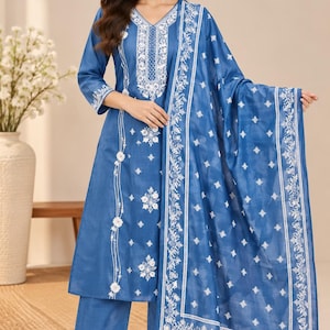 Könnte beinhalten: Ein dreiteiliges blaues Outfit bestehend aus einem langärmeligen Kurta mit V-Ausschnitt, einer passenden Hose mit weitem Bein und einem großen rechteckigen Dupatta. Das Set zeigt aufwendige weiße Blumenstickereien am Ausschnitt, an den Ärmelbündchen und am Saum.