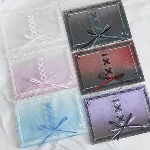 Peut inclure: Plusieurs cadres photo décoratifs aux couleurs variées, dont blanc, rose, bleu, gris et violet. Chaque cadre est orné d'une bordure en dentelle, d'un ruban et d'un motif de style corset. Les cadres sont conçus pour contenir de petites photos ou cartes.
