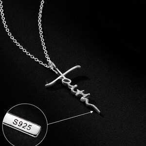 May include: A silver-colored necklace with a cross pendant. The word "faith" is written across the cross. The chain is delicate, and the pendant is detailed. The image also shows a close-up of a tag that reads "S925".