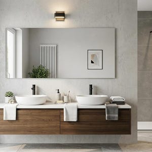 Puede incluir: Un moderno mueble de baño con dos lavabos blancos, grifos negros y un gran espejo rectangular. El mueble tiene un mueble de madera con cajones y una encimera blanca. Se ve una ducha con un cabezal de ducha negro y una puerta de cristal.