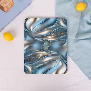 May include: A rectangular tablet case featuring a metallic, liquid-like abstract pattern in shades of silver, chrome, and deep blue. The design displays smooth, flowing curves and reflective highlights that create a sense of depth and movement.