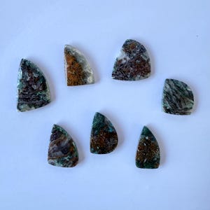 May include: Seven polished, teardrop-shaped stones featuring a mix of deep green, brown, and translucent white mineral inclusions. Each piece displays a unique, organic pattern of dark veining and earthy tones with a smooth, glossy surface finish.