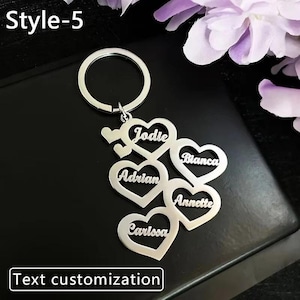 May include: A silver-colored keychain with heart-shaped charms, each bearing a name: Jodie, Adrian, Carlossa, Bianca, and Annette. The keychain includes the text "Text customization" and "Style-5".