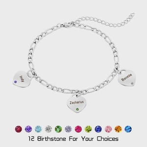 Könnte beinhalten: Ein silberfarbenes Kettenarmband mit drei herzförmigen Anhängern, die mit den Namen Indy, Zacharius und Bennie graviert sind. Jeder Herzanhänger ist mit einem kleinen farbigen Edelstein verziert. Darunter befinden sich zwölf Geburtssteinoptionen.
