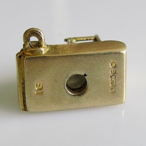 May include: Gold charm in the shape of a vintage sewing machine. The charm has a loop for attaching to a bracelet or necklace. The back of the charm is stamped with "9ct" and "1g".