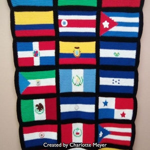Puede incluir: Una manta de ganchillo con las banderas de varios países de América del Sur y Central. La manta está hecha con hilo de colores y tiene un borde negro alrededor de cada bandera. El texto "Creado por Charlotte Meyer" es visible en la parte inferior de la manta.
