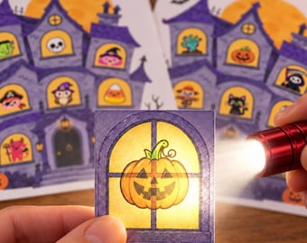 May include: A square card featuring a cartoon jack-o'-lantern in a window, illuminated by a red flashlight. In the background, two larger cards display a purple haunted house illustration with various Halloween characters in the windows.
