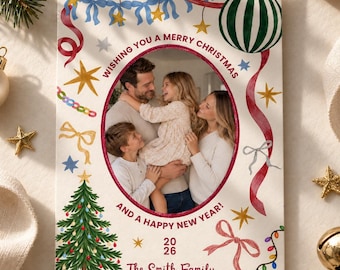 May include: A rectangular Christmas card featuring a central oval photo of a family. The border is decorated with watercolor illustrations of red ribbons, blue bows, gold stars, a green striped ornament, a Christmas tree, and lights. Text reads: WISHING YOU A MERRY CHRISTMAS AND A HAPPY NEW YEAR! 2026 The Smith Family.
