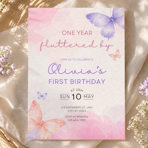 May include: A rectangular birthday invitation card featuring watercolor pink and purple butterfly illustrations. The text reads: ONE YEAR fluttered by, JOIN US TO CELEBRATE Olivia's FIRST BIRTHDAY, AT 2PM SUN 10 MAY, 123 ANYWHERE ST...ANY CITY ST 12345, RSVP to AMANDA 123-456-7890.