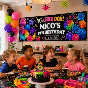 May include: A large black rectangular birthday banner featuring the text YOU NEE DOH! NICO'S 6TH BIRTHDAY LET'S PARTY! surrounded by colorful illustrations of sensory toys, cubes, and fruit shapes against a dark background.