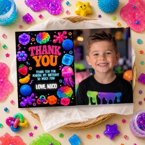 May include: A rectangular birthday thank you card featuring a black background with colorful illustrations of slime, fidget toys, and a strawberry. The text reads: THANK YOU, THANK YOU FOR MAKING MY BIRTHDAY SO MUCH FUN! LOVE, NICO. Includes a photo of a boy.