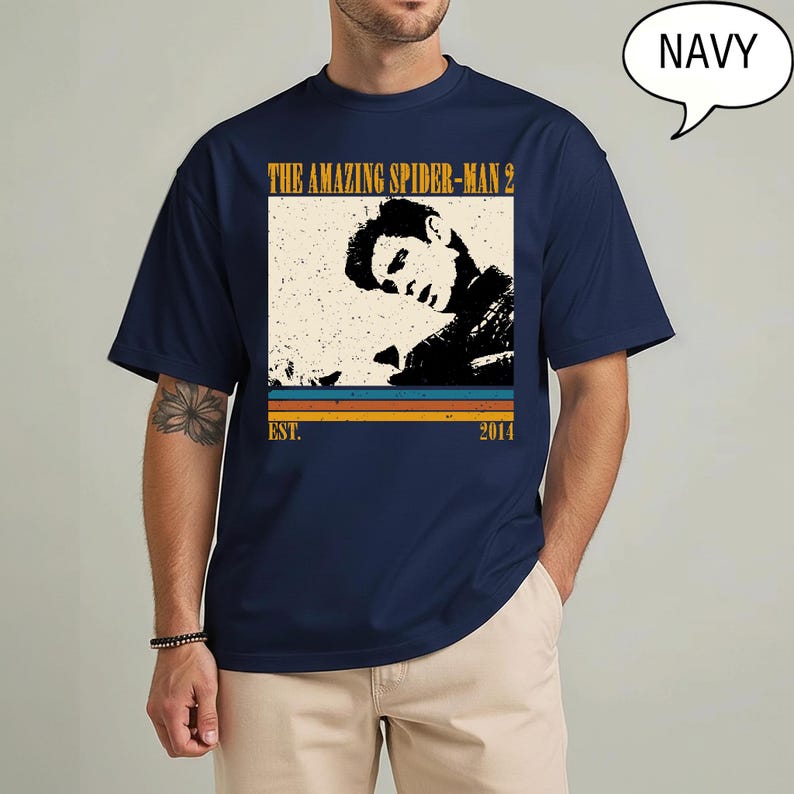 May include: Navy blue t-shirt with a vintage graphic from "The Amazing Spider-Man 2". The design includes a black and white image of a person, the film title, and the year 2014. The shirt has short sleeves and a round neck.