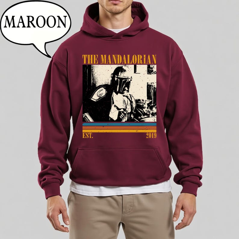 Może przedstawiać: Bordowa bluza z kapturem z grafiką The Mandalorian. Projekt zawiera wizerunek postaci, napis "THE MANDALORIAN" oraz rok "2019". Bluza posiada przednią kieszeń i kaptur ze sznurkiem.