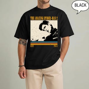 May include: Black t-shirt with a vintage graphic from "The Amazing Spider-Man 2". The design includes a sepia-toned image of a person, the film title, and the year 2014. The word "BLACK" is in a speech bubble.