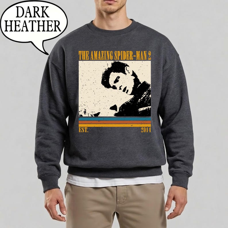 May include: Dark grey sweatshirt with a vintage-style graphic from "The Amazing Spider-Man 2". The design includes a black and white image of a person, the film title, and the year 2014.