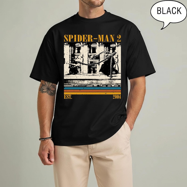May include: Black t-shirt featuring a graphic from the movie Spider-Man 2. The design includes the movie title, a building scene, and the text "EST. 2004" in a retro style. The shirt has a crew neck.