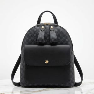 May include: Black backpack with a geometric pattern and a front flap pocket. The backpack has a top handle and adjustable shoulder straps. The flap pocket is secured with a gold-colored button. The backpack is made of a durable material.
