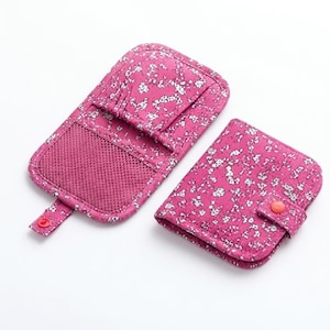 May include: Two rectangular pouches in a vibrant magenta fabric with a white floral pattern. One pouch is open, revealing a mesh pocket and a snap-button tab. The second pouch is folded closed and secured with a matching magenta snap-button strap.