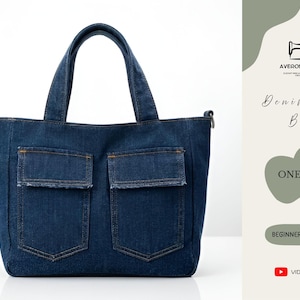 Op de afbeelding: Een donkerblauwe denim tote bag met twee voorzakken. De tas heeft stevige handvatten. De tekst "Denim Tote Bag" en "One Size" is ook zichtbaar. Geschikt voor dagelijks gebruik.