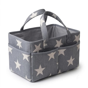 May include: A rectangular fabric storage caddy in a grey color featuring a white star pattern throughout. The organizer includes two sturdy fabric handles and two exterior pockets on the front side, with a solid grey interior lining and trim.