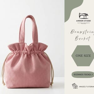 Puede incluir: Bolso tipo cubo rosa de pana con cordón, diseño estructurado y dos asas superiores. El bolso tiene una parte superior fruncida y un cierre de cordón. El texto "Drawstring Bucket" y "One Size" son visibles.