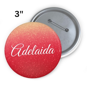 May include: A 3-inch round button with a glittery red and orange gradient background. The word "Adelaida" is written in white cursive script across the front. The back of the button is silver with a pin.