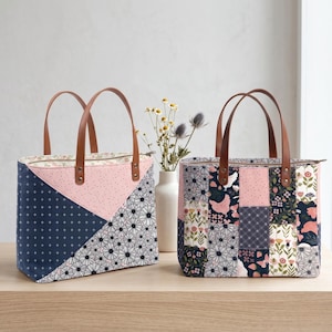 Könnte beinhalten: Zwei Tragetaschen mit Patchwork-Designs. Eine Tasche hat ein marineblaues, rosa und weißes Blumenmuster, die andere ein marineblaues, rosa und weißes Gänseblümchenmuster. Beide Taschen haben braune Ledergriffe und stehen auf einer Holzoberfläche.