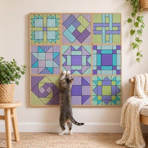 May include: A wall hanging featuring nine square quilt blocks with geometric designs in shades of purple, blue, and green. A gray tabby cat stands on its hind legs, reaching up to the quilt.
