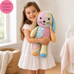 May include: A colourful patchwork bunny toy with a pink, blue, yellow, and orange design. The bunny is held by a person wearing a white dress. The text "Finished Product Display" is in a pink circle in the upper left corner of the image.