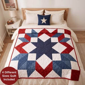 May include: A quilt featuring a large central star pattern in navy blue with white dots, surrounded by geometric shapes in solid red, navy blue, and white with subtle patterns. The quilt is spread over a bed with white pillows and a navy blue accent pillow.