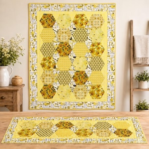 May include: A rectangular quilt and a matching table runner featuring a yellow and white honeycomb pattern. The fabric displays various bee, sunflower, and geometric prints with a border containing the text Pure Honey, Bee, and Buzz.