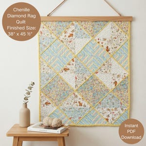 May include: A chenille diamond rag quilt with a finished size of 38 inches by 45.5 inches, featuring a patchwork design of floral, striped, and animal-patterned fabric squares in shades of blue, yellow, white, and orange, hung on a wooden frame.