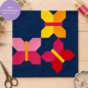May include: A square, navy blue fabric block with four colorful butterfly designs. The butterflies are yellow, orange, pink, and red, with yellow and orange accents. The block's unfinished size is 12.5 x 12.5 inches. Sewing notions are in the background.