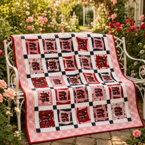 May include: A patchwork quilt featuring a grid of square blocks in shades of red, pink, white, and black. The design includes floral and patterned fabric squares separated by small black squares, finished with a pink and white plaid border.