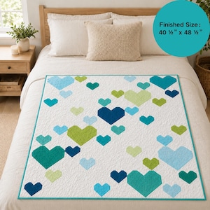 Peut inclure: Une courtepointe blanche ornée d'un motif dispersé de cœurs dans diverses nuances de bleu et de vert. La courtepointe présente une bordure sarcelle et une taille finie de 102,87 cm sur 123,19 cm, comme indiqué sur l'encart circulaire.
