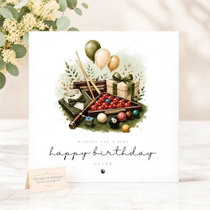 May include: A square birthday greeting card featuring a watercolour illustration of billiard equipment including a rack of red balls, a blue ball, a black eight ball, two cues, a green bow tie, a gift box, and balloons. Text reads: WISHING YOU A VERY happy birthday CLIVE.