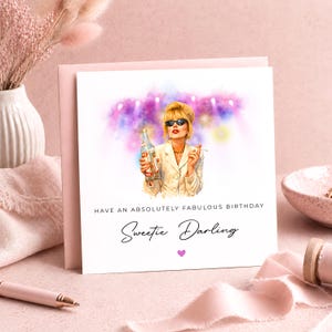 May include: A birthday card with an illustration of a woman in sunglasses holding a bottle and cigarette. The card reads "Have an absolutely fabulous birthday Sweetie Darling" with a pink heart. The card is on a pink background.