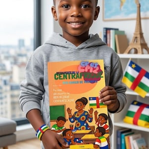May include: A young child smiles while holding a book titled "Découverte de la Centrafrique". The book cover features illustrations of people and the Central African Republic flag. The child wears a gray hoodie, denim shorts, and a beaded bracelet.