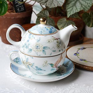 May include: A set of three ceramic mugs with a speckled, matte finish. The mugs are in shades of cream, light gray, and dark gray. Each mug has a simple, minimalist design, perfect for coffee or tea.