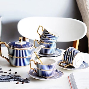 Könnte beinhalten: Ein Set aus drei Keramikbechern mit gesprenkelter, matter Oberfläche. Jeder Becher hat eine andere Farbe: hellblau, cremefarben und grau. Die Becher haben ein schlichtes, modernes Design und einen bequemen Griff.