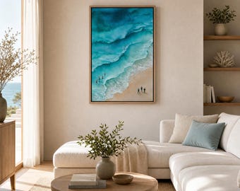 May include: A vertical framed wall art print depicting an aerial view of a sandy beach with turquoise ocean waves crashing against the shore. Several small figures are visible walking along the water's edge, captured in a realistic style.