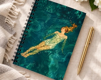 May include: A spiral-bound notebook featuring a cover illustration of a person with long hair floating in deep teal water. The person wears a light-colored swimsuit, and the water surface shows light reflections and ripples across the scene.