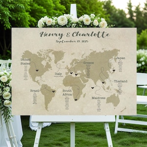 Può includere: Un tableau segnaposto a forma di mappa del mondo beige su un cavalletto bianco, decorato con fiori bianchi. La mappa presenta nomi di paesi e linee tratteggiate. I nomi "Henry & Charlotte" e la data "19 settembre 2025" sono in alto.
