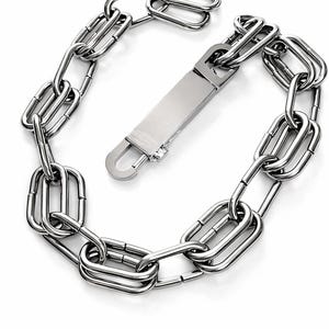Puede incluir: Un collar de cadena plateada con un cierre rectangular. Los eslabones de la cadena son alargados y rectangulares. El cierre es una pieza plana y rectangular con un gancho curvo. El collar está hecho de un material metálico brillante.