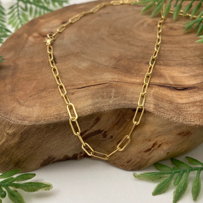 May include: A gold chain necklace with a delicate, linked design. The chain is made of small, oval-shaped links.