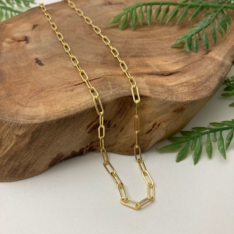 May include: A gold chain necklace with a delicate, linked chain design. The chain is made of small, oval-shaped links.