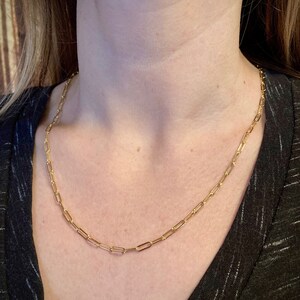 May include: A gold chain necklace with a simple, linked design. The chain is made of small, oval-shaped links.
