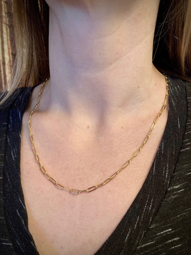 May include: A gold chain necklace with a simple, linked design. The chain is made of small, oval-shaped links.