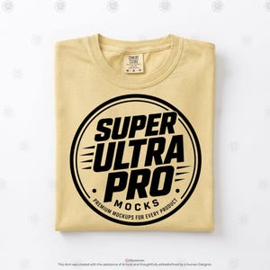 May include: A light yellow t-shirt featuring a black circular graphic on the chest. The graphic contains the bold text SUPER ULTRA PRO MOCKS and the smaller text PREMIUM MOCKUPS FOR EVERY PRODUCT. The shirt has a Comfort Colors brand label.